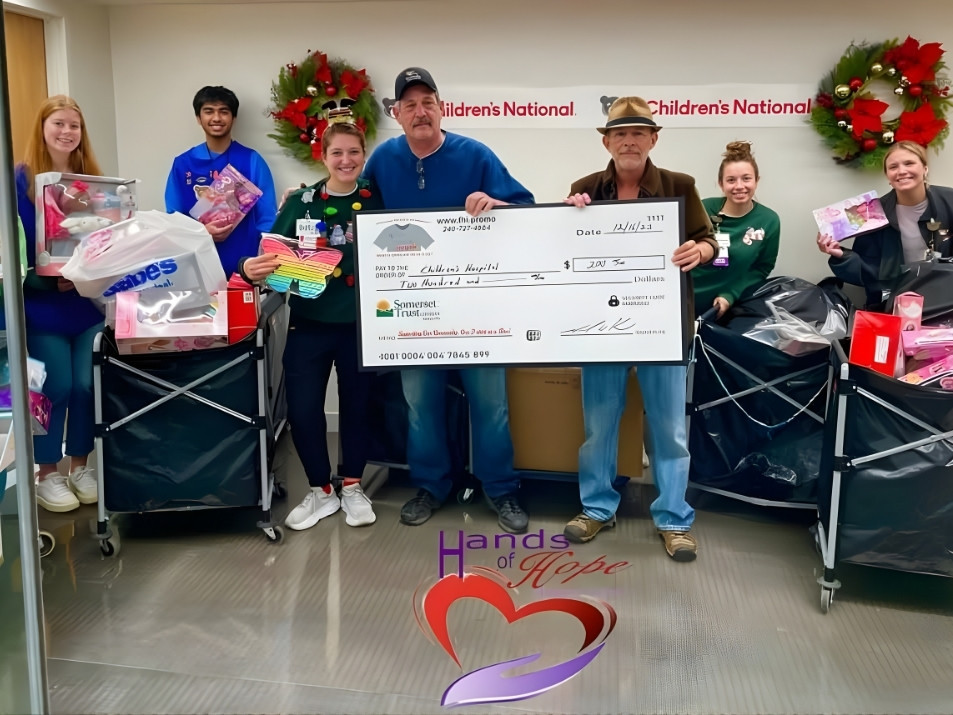 Six people pose together while holding a $2,000 ceremonial check from Hands of Hope made out to the Schwab Family Cancer Cente